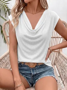 Détail d'un haut blanc sans manches avec col bénitier et décorations en strass brillants.