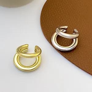 Detailed macro view of minimalist double-layered gold and silver ear cuffs on brown leather