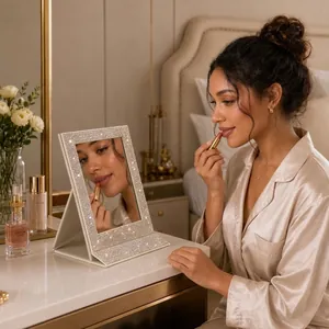 Gros plan d'une femme utilisant le miroir de maquillage pliable à strass dans sa chambre.