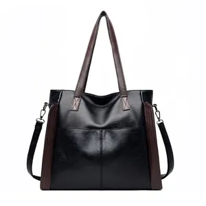Front view of a large black soft leather tote bag with brown straps and side accents