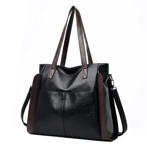 Three-quarter view of a large black leather tote bag with contrasting brown handles and strap