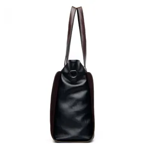 Side profile detail of a spacious soft black leather tote bag with dark brown handles