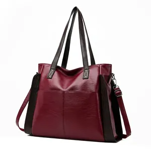 Side view detail of a large wine red soft leather tote bag with dark brown straps