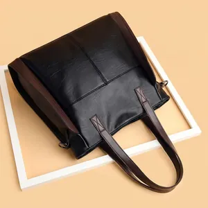 Close-up view of a large capacity soft leather tote bag with elegant contrast brown trim