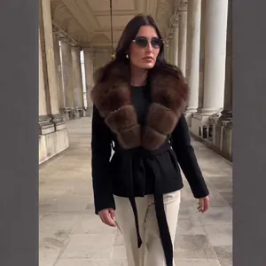 Elegante abrigo de lana negro con cuello grande de piel sintética marrón y cinturón.