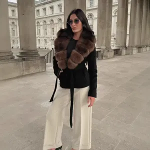 Mujer elegante con un abrigo de lana negro con un lujoso cuello de piel sintética marrón.