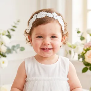 Detailed view of a sweet baby girl wearing an elegant white floral lace embroidery headband.