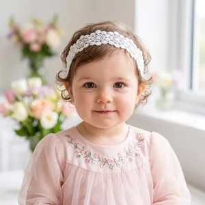 Detail view of a soft white lace headband for babies featuring intricate floral patterns