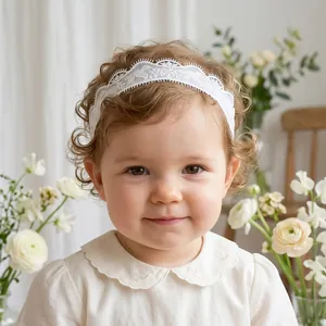 Close-up detail of white delicate lace baby headband with floral embroidery on a toddler