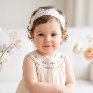 Close-up of a baby girl wearing a delicate white lace headband for a photo shoot.