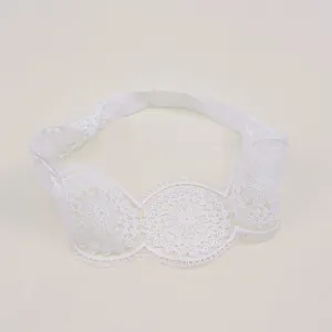 Detailed view of white lace baby headband with elegant floral embroidery patterns