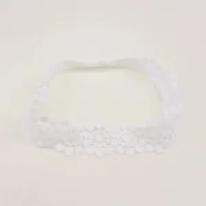 Close-up of white baby lace headband featuring delicate embroidered flower patterns.