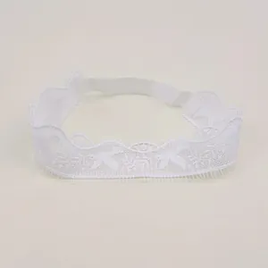 Close-up of intricate floral embroidery on white lace texture for baby headwear