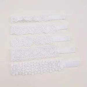 Close-up of white lace baby headbands with various floral and butterfly embroidery patterns.