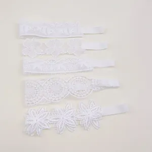 Close-up detail of five white lace baby headbands featuring elegant floral embroidery