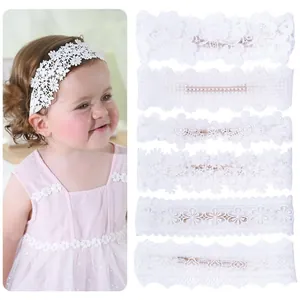 Detail view of various white lace flower embroidered baby headbands for photography