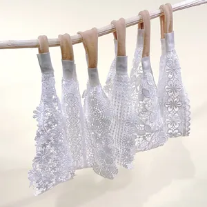 Detail view of multiple white lace baby headbands with delicate floral embroidery patterns.