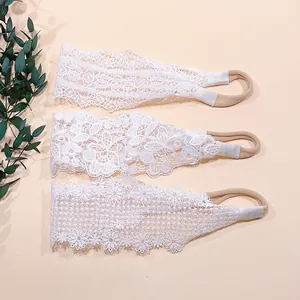 Detailed view of three white floral lace baby headbands with soft nylon elastic bands