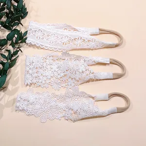 Detailed view of three white floral lace baby headbands with delicate embroidery