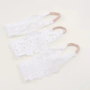 Detail view of three white lace baby headbands with intricate floral embroidery