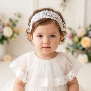 Close-up detail of the white embroidered floral lace headband worn by a toddler girl