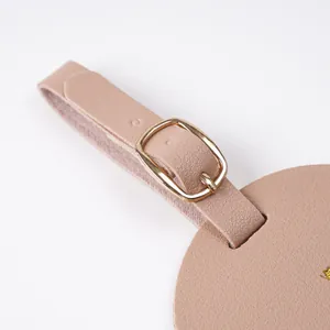 Detailed close-up view of pink faux leather luggage tag featuring a golden metal buckle