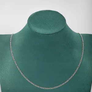 Close-up detail of a minimalist silver stainless steel 3:1 Figaro chain necklace on a bust