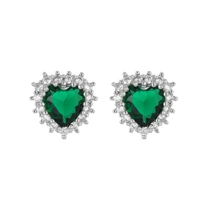 Detailed macro view of emerald green heart-shaped stud earrings with cubic zirconia halo