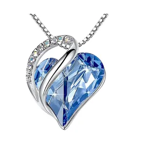 Close-up of heart-shaped pendant with faceted blue birthstone and crystal accents