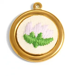 Détail de la broderie florale faite main sur un pendentif en acier inoxydable doré