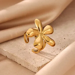 Detailed macro view of a polished gold stainless steel flower ring on stone surface.