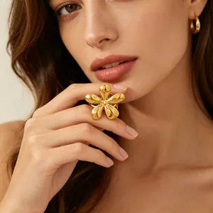 Detail of a stylish large gold flower ring made of stainless steel worn on a finger.
