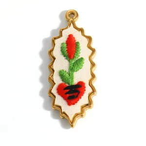 Vue détaillée d'un pendentif en forme de cœur avec fleur brodée et cadre en métal doré