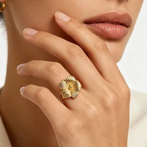 Elegant detail view of a gold-plated stainless steel flower ring worn on a hand.