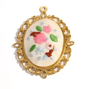 Détail d'un pendentif fleur brodée de style champêtre avec cadre en acier inoxydable doré