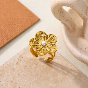 Detailed macro view of a golden stainless steel flower ring featuring a central pearl accent