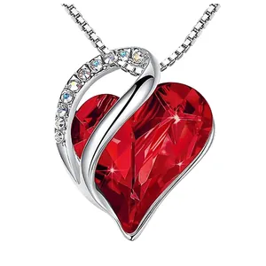 Close-up of heart-shaped red faceted birthstone pendant with pave crystal accents