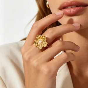 Detailed macro view of a gold plated flower ring with pearl worn on model's finger
