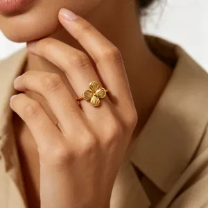 Close-up of a delicate gold flower ring with textured petals worn on a model finger