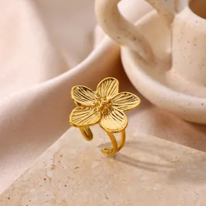 Detailed view of an elegant gold stainless steel flower ring resting on a stone surface.