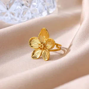Detailed macro view of an elegant gold stainless steel flower ring on silk fabric.