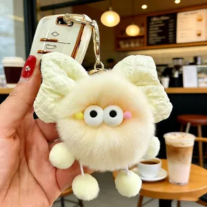 Dettaglio di portachiavi mostro peluche carino con fiocco decorativo e grandi occhi