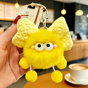 Dettaglio di un simpatico portachiavi mostro giallo soffice con un grande fiocco giallo