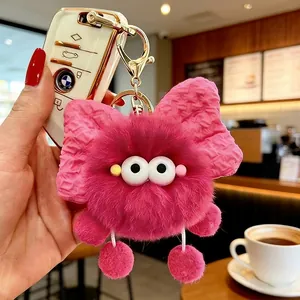 Dettaglio ravvicinato di un simpatico portachiavi in peluche rosa con un elegante fiocco.