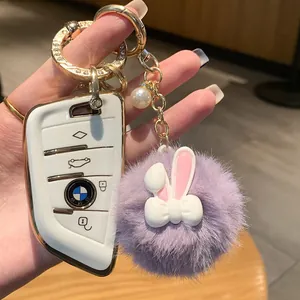 Vista dettagliata della cover per chiave auto bianca con portachiavi a pompon viola