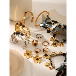 Colección de pulseras y anillos de piedra ojo de tigre en oro y plata sobre bloques decorativos