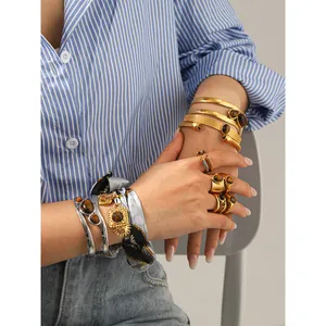 Detalle de pulseras y anillos de acero inoxidable con piedras de ojo de tigre para mujer