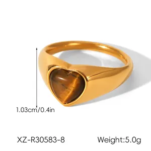 Vista detallada de un anillo de piedra de ojo de tigre con forma de corazón en acero dorado