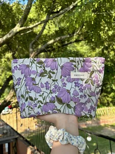 Detailed view of a purple floral embroidered makeup bag with H&R BAG woven label