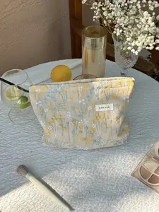 Close-up of floral embroidery on a beige linen makeup pouch with H&R BAG logo